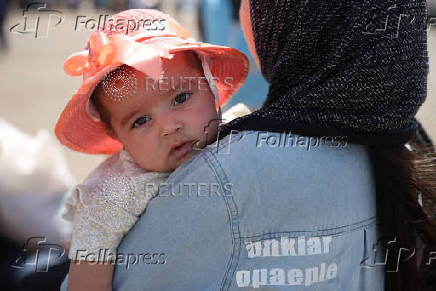 An Afghan woman, who was deported from Iran, holds her baby at a camp for returning migrants near the Islam Qala border crossing