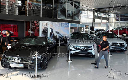 FILE PHOTO: A person walks past Mercedes-Benz cars on display, in Johannesburg