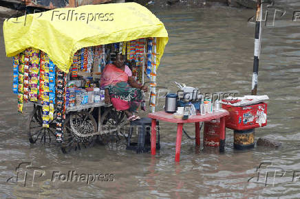 A woman vendor sits in her shop cart, as streets are flooded after torrential rains, in Ahmedabad