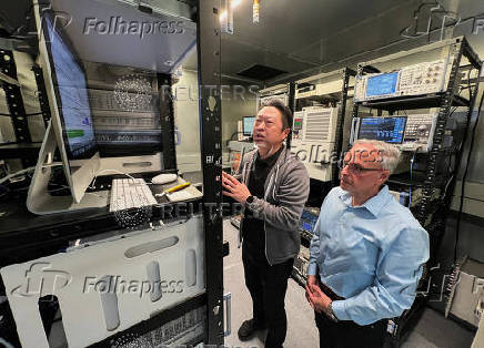 FILE PHOTO: Johny Srouji (R), senior vice president of hardware technologies at Apple, and an Apple engineer view testing data on Apple's new C1 cellular modem, in Sunnyvale