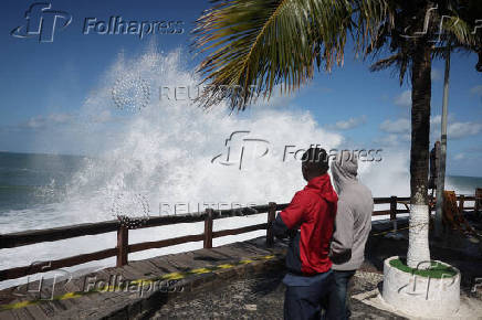 People stand at a viewpoint on Leblon beach amid big waves in Rio de Janeiro