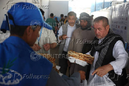 Afghan nationals, who were deported from Iran, receive food inside a UNHCR tent at a camp for returning migrants near the Islam Qala border crossing