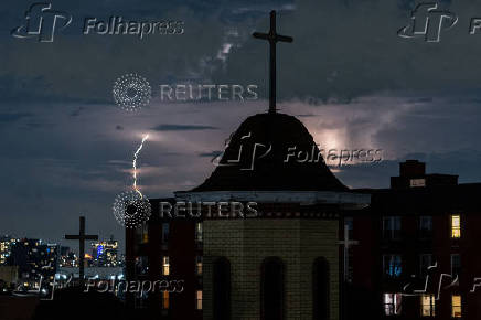 Lightning illuminates the sky behind a church in New York