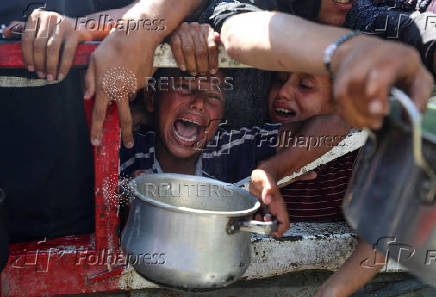Palestinians wait to receive food from a charity kitchen, in Gaza City