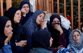 People gather near the bodies of Palestinians killed in Israeli strikes, in Khan Younis