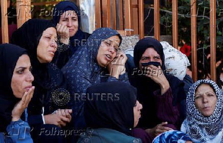 People gather near the bodies of Palestinians killed in Israeli strikes, in Khan Younis