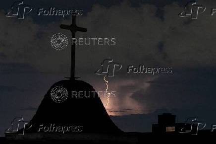 Dry lightning illuminates the sky behind a cross in New York
