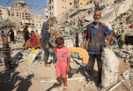 Palestinians inspect the site of an Israeli air strike that destroyed a residential building, in Gaza City