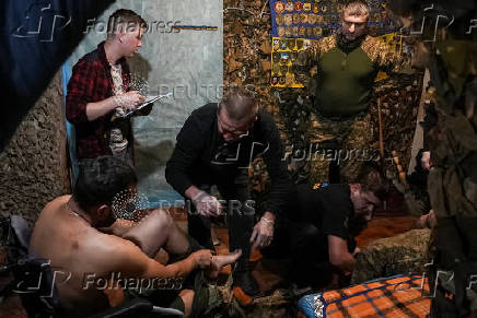 Medics help a wounded Ukrainian serviceman at a medical stabilisation point, near the town of Pokrovsk, in Donetsk region