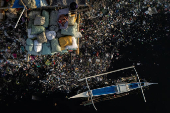 A boy sleeps on sacks of garbage along the polluted Pasig River on World Environment Day in Manila