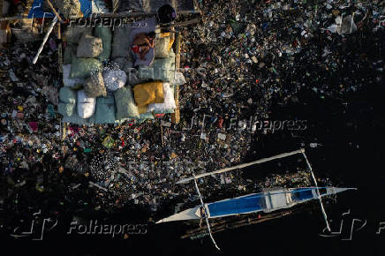 A boy sleeps on sacks of garbage along the polluted Pasig River on World Environment Day in Manila