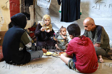 Fatima Arafa, a pregnant and displaced Palestinian woman, eats a meal inside her tent, where she has taken shelter with her family after fleeing their home, in Gaza