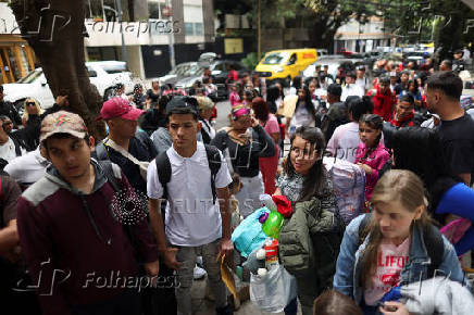 Migrants gather outside the Venezuelan embasssy waiting for a flight back to their country