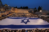 People hold a giant Israeli flag by the Western Wall, in Jerusalem's Old City