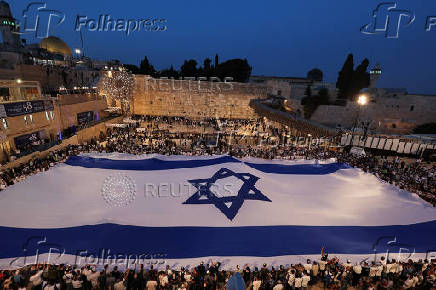 People hold a giant Israeli flag by the Western Wall, in Jerusalem's Old City