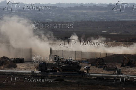 A truck carrying an armoured personnel carrier (APC) drives on the Israeli side of the Israel-Gaza border