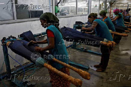 Workers use sand paper on jeans to fade colour in a garment manufacturing unit on the outskirts of Ahmedabad