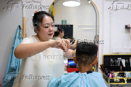 Hair salon owner Xueru gives a child a haircut in a design of a tank to commemorate the 80th anniversary of the end of World War Two in Beijing