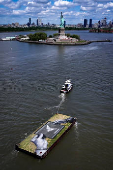 Drone view shows a grass covered barge with painting by Franco-Swiss artist Saype entitled ?Address Hate? towed past Statue of Liberty in New York Harbor