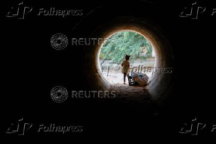 A child stands inside a makeshift tunnel made from a truck cargo trailer buried under dirt, where they hide when a rocket siren alert sounds for a missile strike from Iran on Israel, in southern Negev