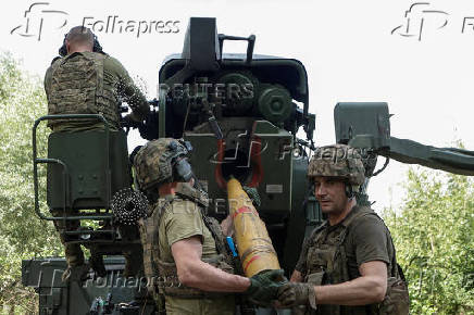 Ukrainian servicemen load a shell into a self-propelled howitzer before firing towards Russian troops near a front line in Kharkiv region