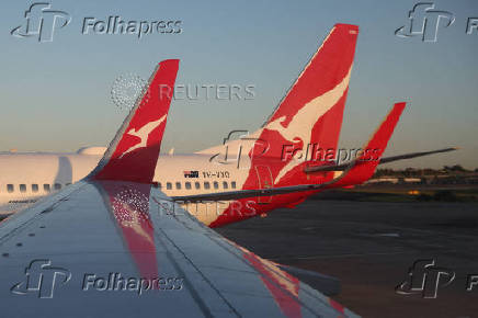 A Qantas logo is visible on the tail of an aeroplane at an airport in Sydney