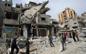 Palestinians inspect the site of an Israeli strike on a house, in Gaza City
