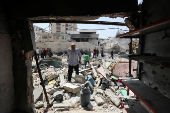Palestinians inspect the damage at the site of an Israeli strike on a house, in Gaza City