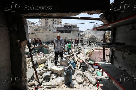 Palestinians inspect the damage at the site of an Israeli strike on a house, in Gaza City