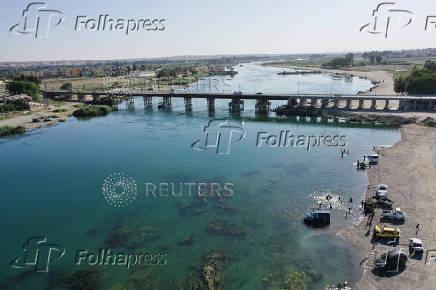 A drone view shows people swimming in the Euphrates River during a hot day in Raqqa