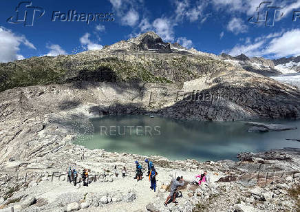 Tourists walk at lake at the bottom of the Rhone glacier amid climate change in Obergoms