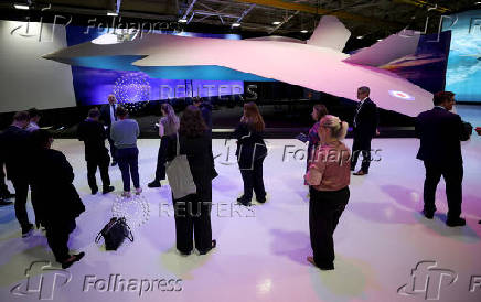 Journalists stand next to a concept model of the new GCAP (Global Combat Air Programme) 6th generation military jet at the BAE Systems Warton factory in Warton, Britain