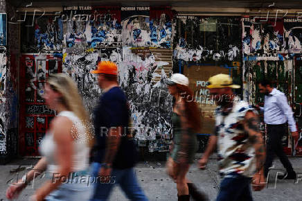 People walk by empty real estate covered in advertisement bills and graffiti in the Tribeca area of New York Cit