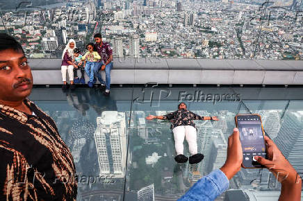 Tourists pose as they enjoy the Mahanakhon Skywalk Rooftop in Bangkok