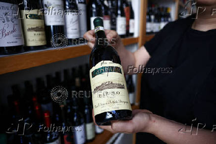 A shop assistant holds a bottle of Italian wine in a store amid threats by U.S. President Donald Trump to impose 30% tariffs on EU imports