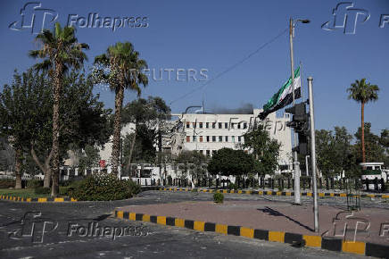 People gather near a damaged site, in Damascus