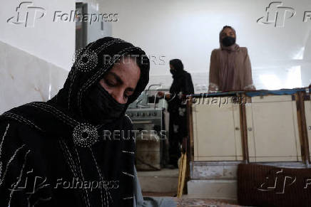 Rahela, 37, an Afghan woman and certified makeup artist and seamstress, who, along with her two daughters, was deported from Iran, sits inside her father's house in Herat