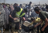 Displaced Palestinians collect donated food in Jabalia, northern Gaza