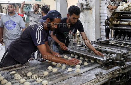 Palestinian workers prepare bread in a bakery that returned to operation after being closed due to a flour shortage, in Deir Al-Balah