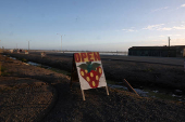 A sign advertising strawberries stands on a roadside, near fields in Oxnard, California
