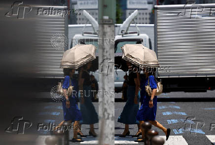 Passersby holding parasols walk on the street in Tokyo