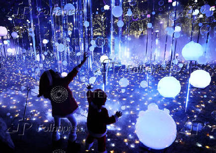 A girl and boy wearing Santa Claus costumes try to catch soap bubbles in the air at an illumination event celebrating the upcoming the Christmas season
