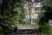 A resident walks at a street near buildings damaged by Russian military strikes in the frontline town of Kostyantynivka
