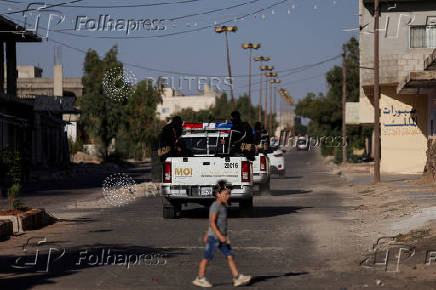 Members of Ministry of Interior (MOI) Internal Security Command ride in trucks at Bosra al-Sham town