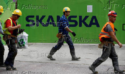 FILE PHOTO: Workers walk past a Skanska logo seen on a fence at a construction site In Warsaw, Poland
