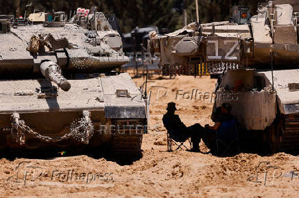 Israeli soldiers rest next to a tank, near the Israel-Gaza border