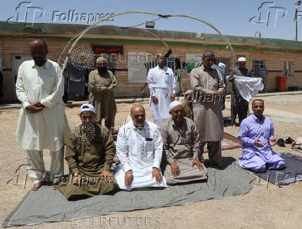 Iranian pilgrims who were rerouted through Iraq pray near the Arar border crossing