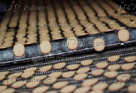 FILE PHOTO: Biscuits pass along a conveyor belt after being baked at the Britannia factory in New Delhi
