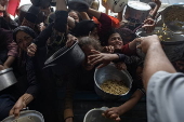 Displaced Palestinians collect donated food in Khan Yunis, southern Gaza