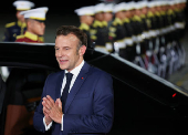 French President Emmanuel Macron gestures upon his arrival at military airbase Halim Perdanakusuma in Jakarta